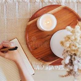 Hand writing in a journal beside a candle—cozy evening writing ritual.