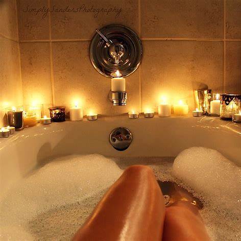 A candlelit bath filled with warm water, foam and glowing candles for a peaceful ritual.