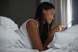 Woman in bed filling out her sleep journal in the morning