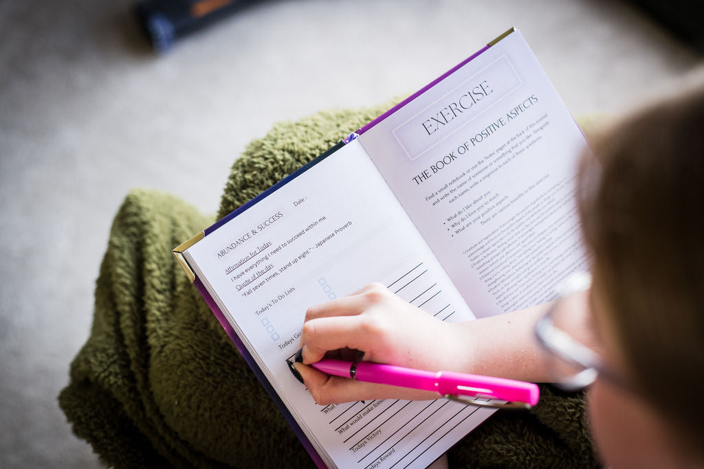 Girl completing her manifestation journal. Abundance and success section.