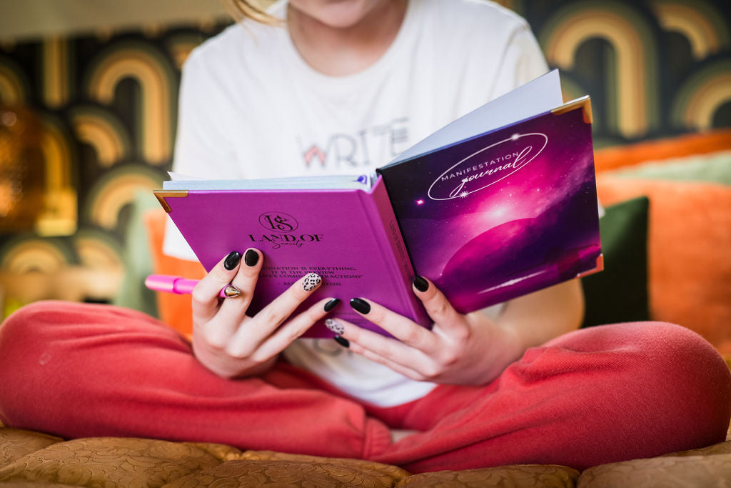 Girl on bed using her journal 
 to manifest her best life.