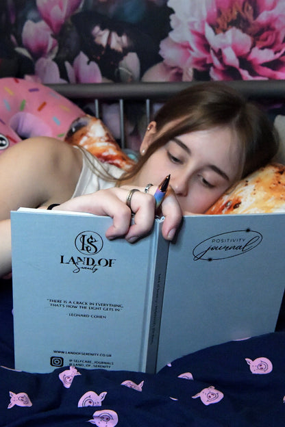 Young woman using her Positivity Journal to reflect upon her day during her bedtime ritual